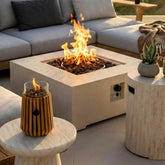 Outdoor setting with a fire pit table, decorative candle, and potted plant.