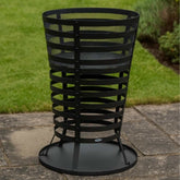 Black metal fire pit on a patio with grass in the background