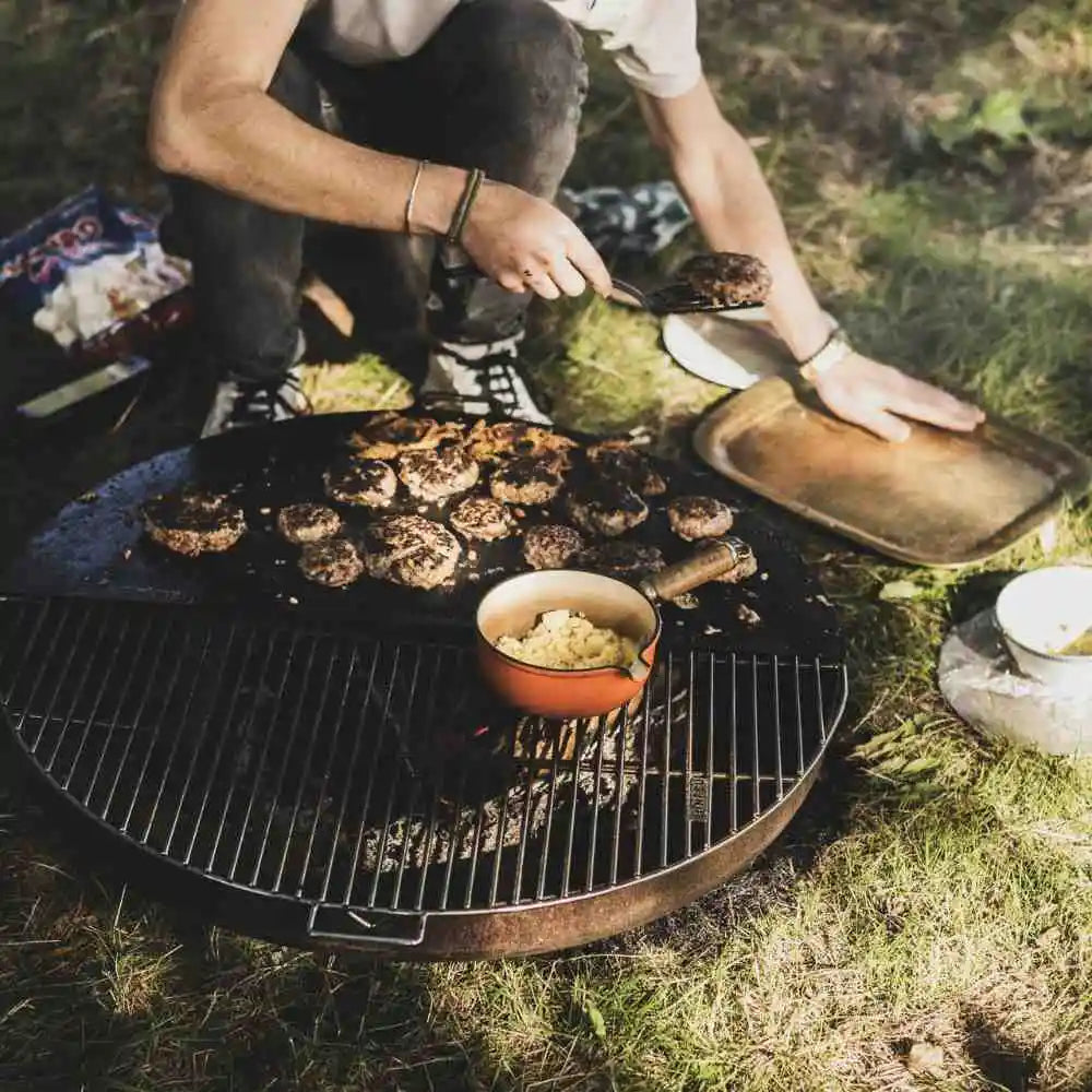Person cooking burgers on a grill outdoors