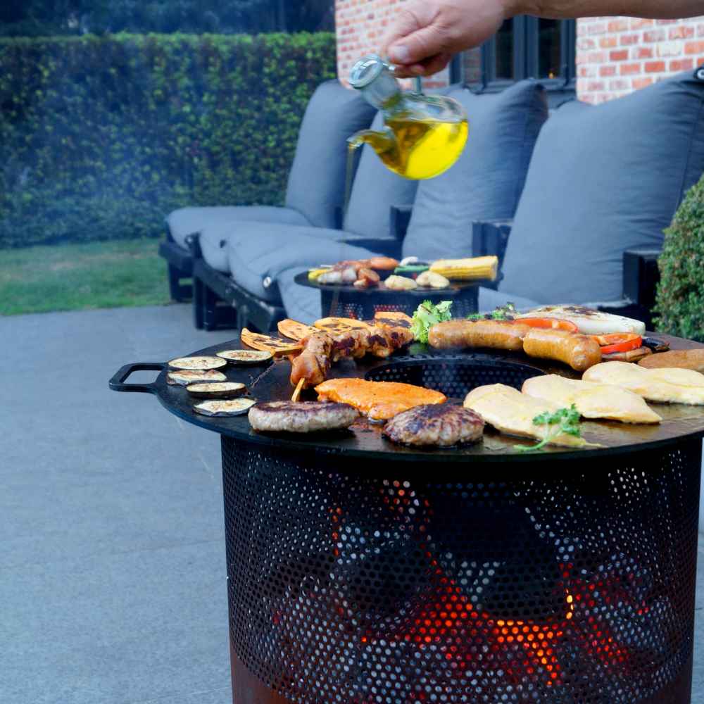 Person pouring oil over food on a grill outdoors