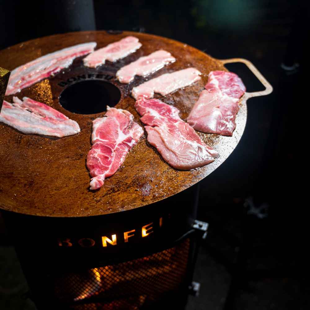 Raw meat slices on a grill with 'Bonfeu' branding.