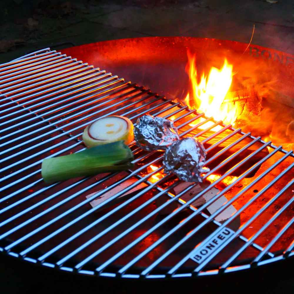 Grill with food items being cooked over an open flame, featuring the brand 'BONFEU'.