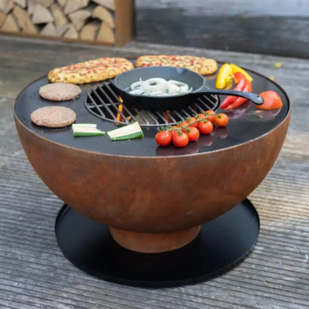 Rust-colored fire pit with food items on a wooden surface