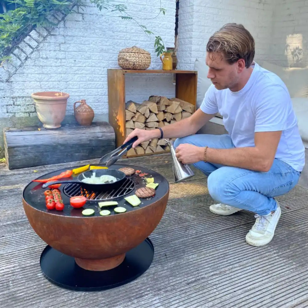 Man grilling vegetables on a fire pit in an outdoor setting