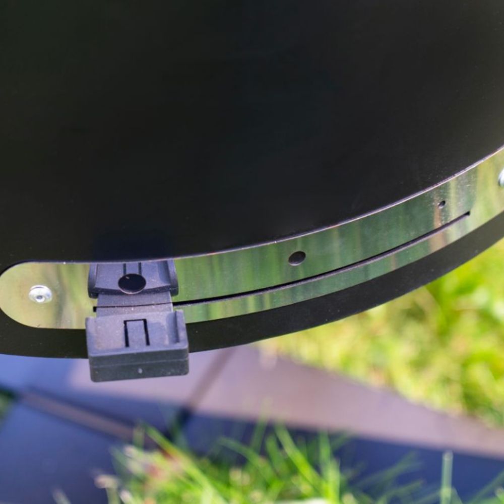 Close-up of a grill lid with a metal handle on a grassy background