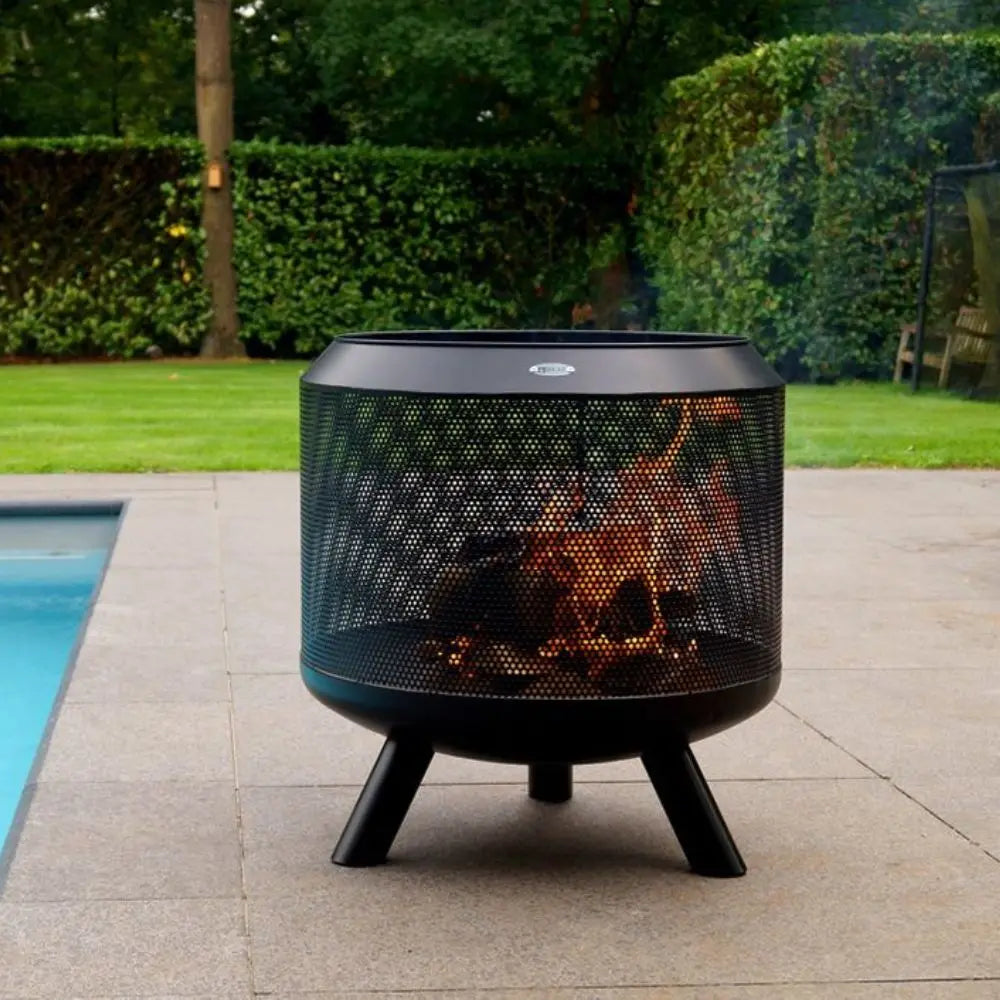 Outdoor fire pit with flames on a patio near a pool