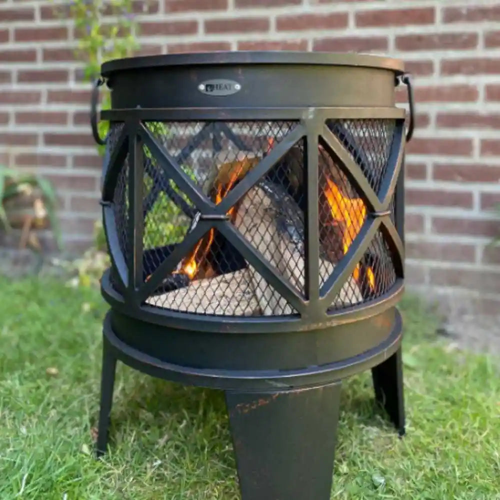 Outdoor fire pit with flames burning on a grassy area with a brick wall background