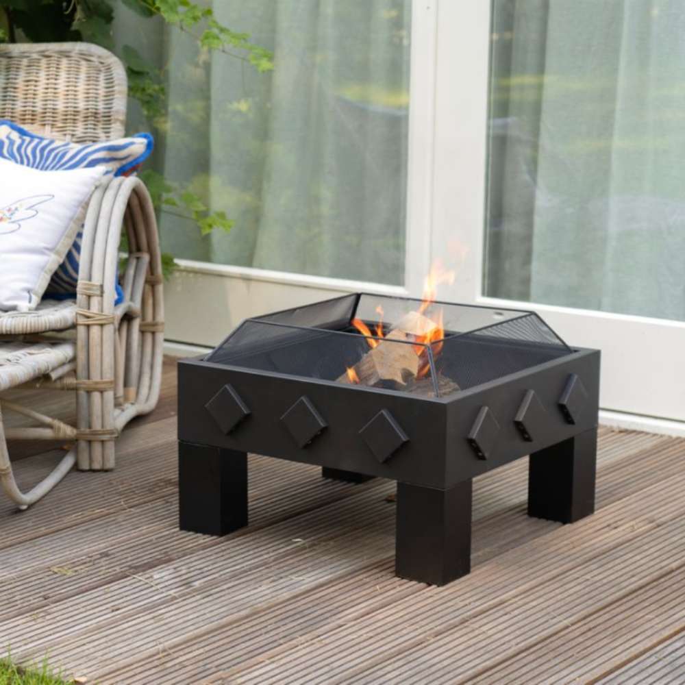 Black outdoor fire pit on a wooden deck with a chair and cushions in the background.