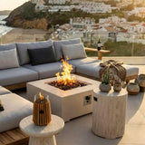 Outdoor patio with fire pit, couches, and scenic view of a coastal town.