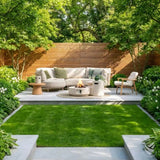 Outdoor patio with a fire pit, sofa, and chairs surrounded by greenery.