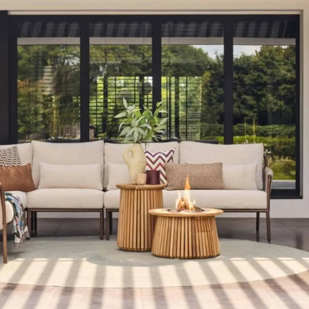 Outdoor patio setting with a beige sofa, fire pit table, and decorative items.