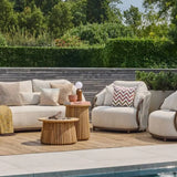 Outdoor patio set with beige furniture, cushions, and a wooden fire pit table by a pool.