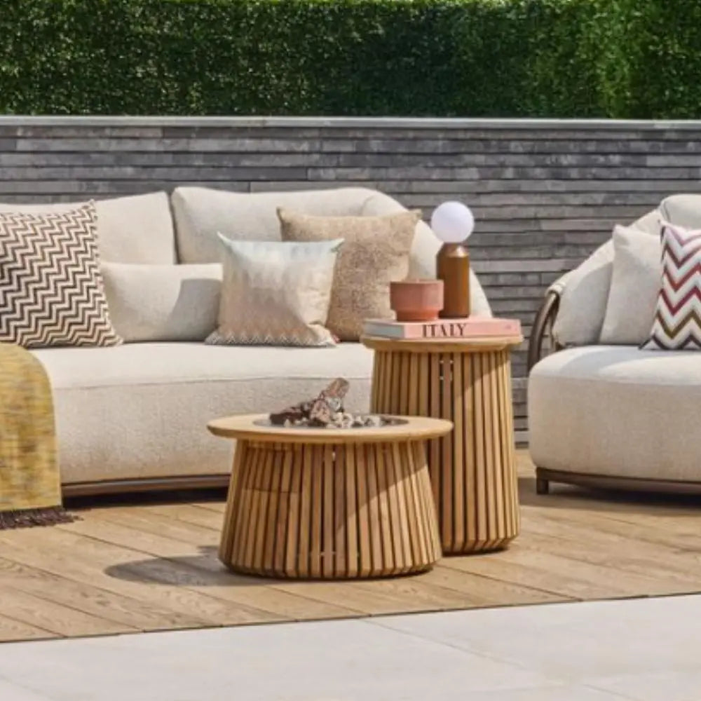 Outdoor patio setting with beige sofas, wooden fire pit tables, and decorative items.