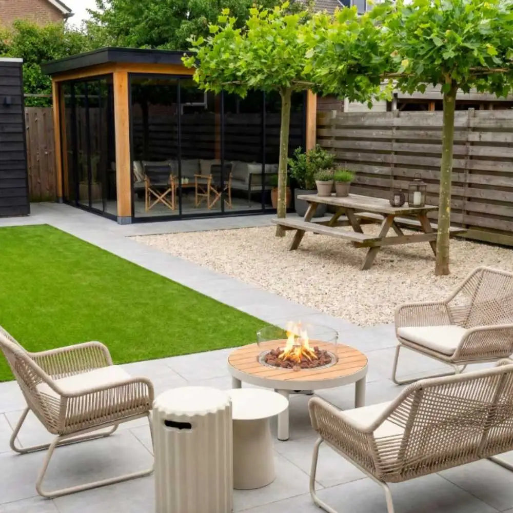 Outdoor patio with fire pit, chairs, and a small building in the background
