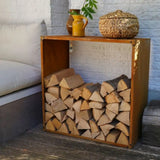 Wooden firewood storage unit with stacked logs against a white brick wall.
