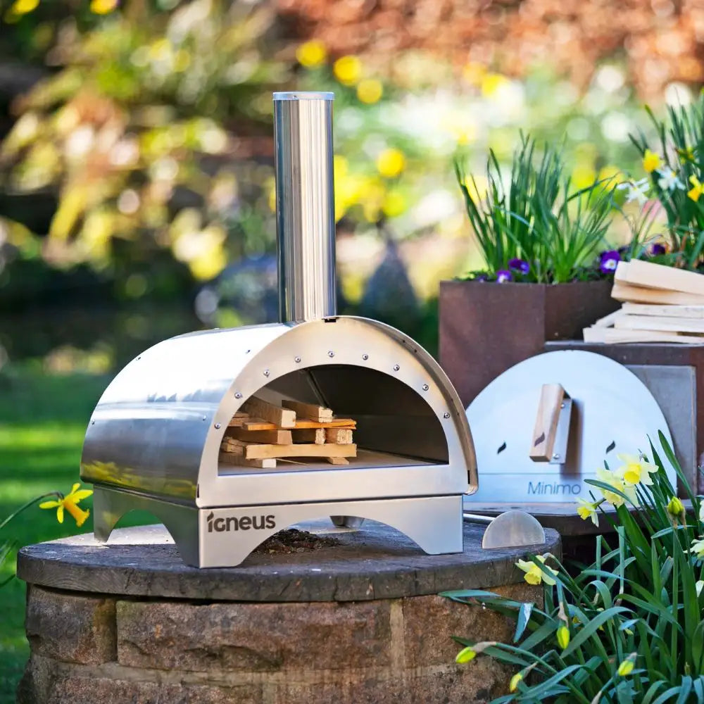 Outdoor pizza oven on a stone platform with garden in the background