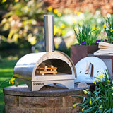 Outdoor pizza oven on a stone platform with garden in the background