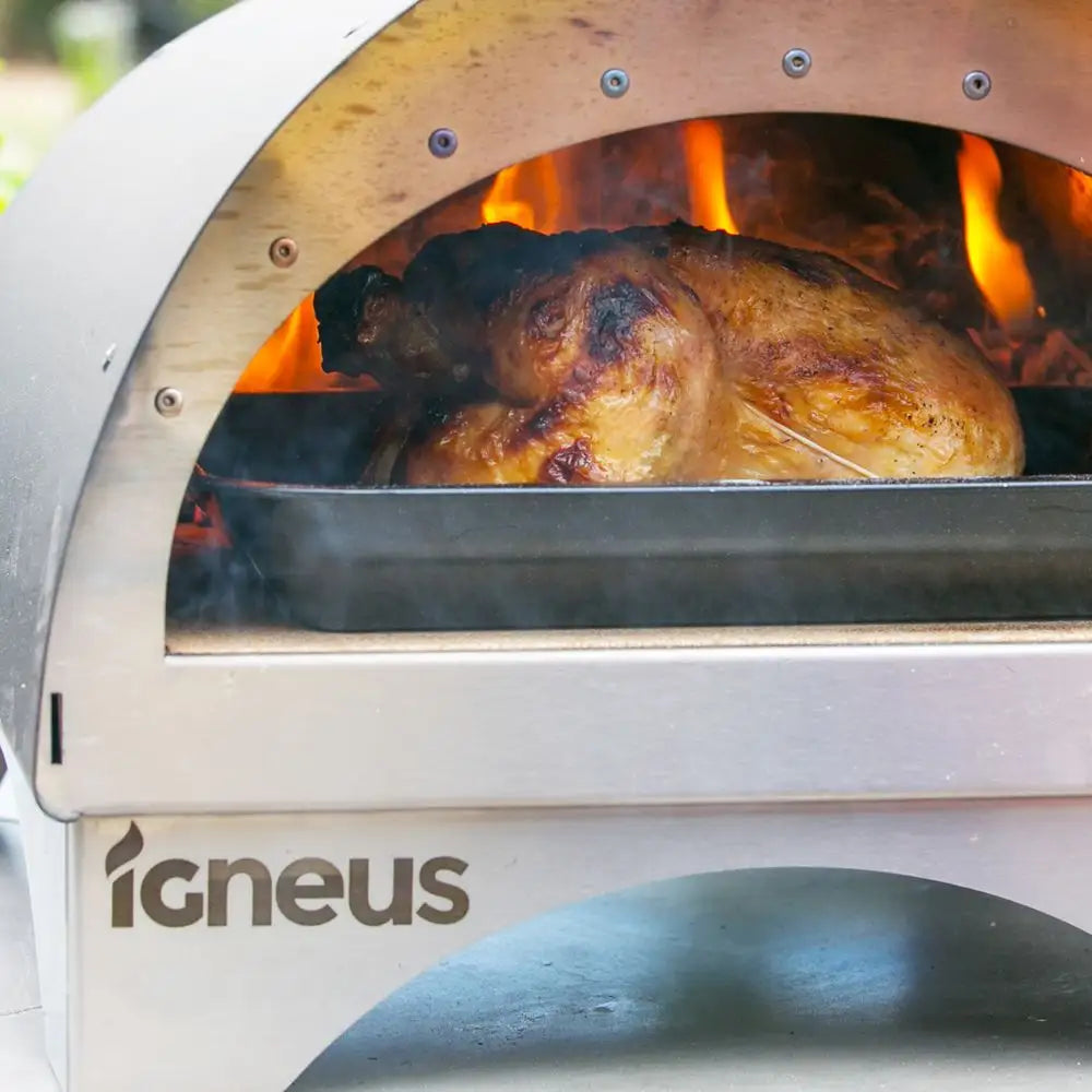 Roasted chicken in an Igneus outdoor pizza oven with visible flames.