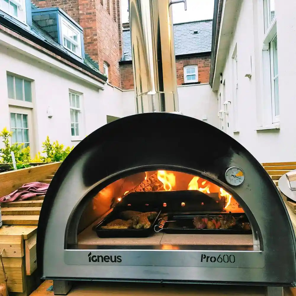 Outdoor pizza oven with flames inside, brand 'igneus' visible, in an urban setting.