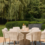 Outdoor dining setup with chairs, table top burner and a table in a garden setting