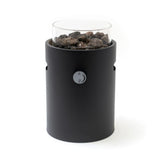 Black cylindrical table top burner with glass cover and rocks on a white background