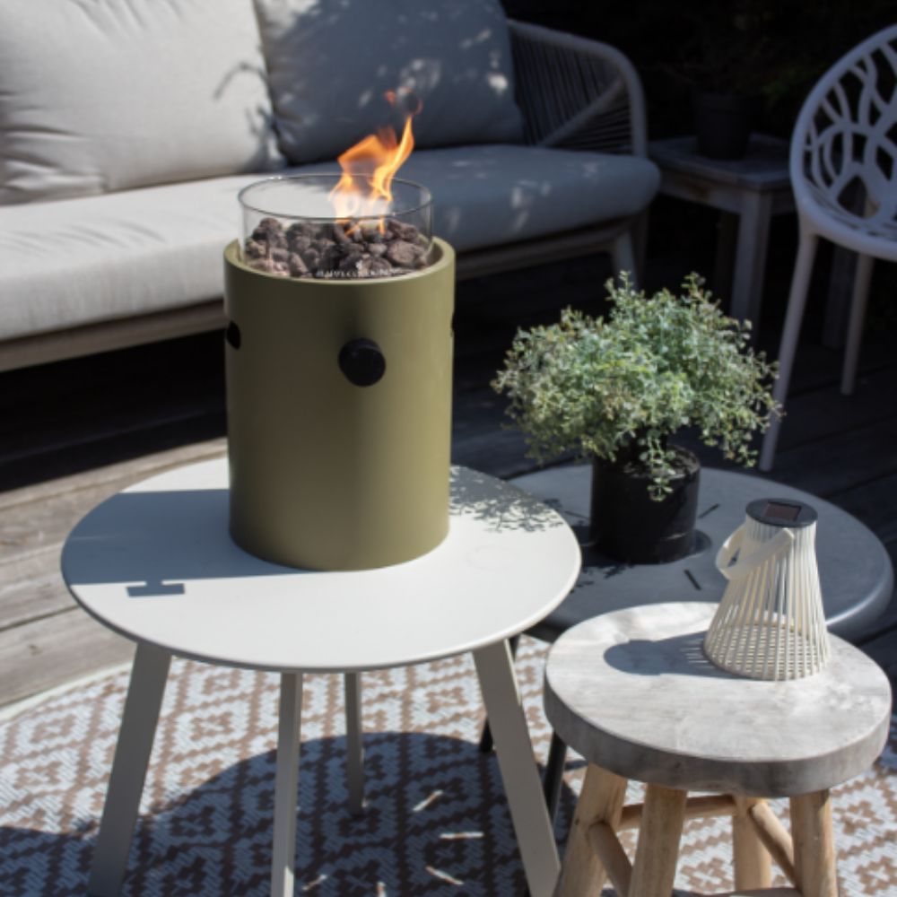 Outdoor setting with a green portable table top burner on a small round table, surrounded by outdoor furniture and decor.