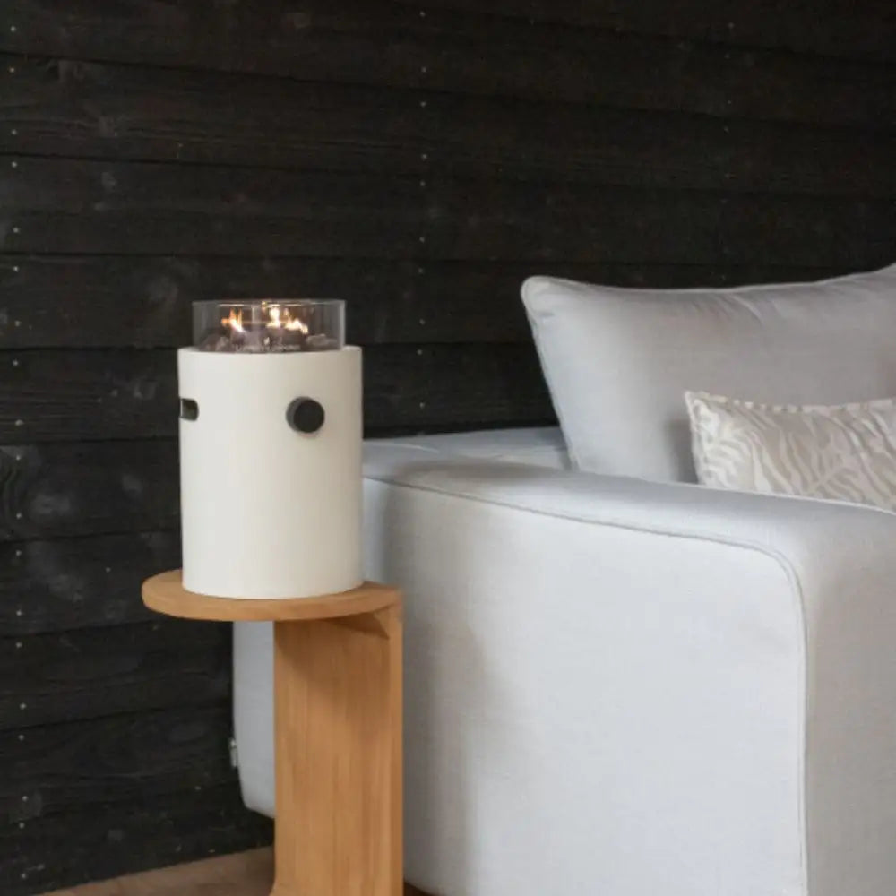 Modern side table with a table top burner next to a white sofa against a dark wooden wall.
