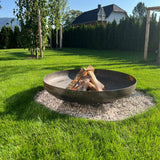 Fire pit with burning logs in a grassy backyard