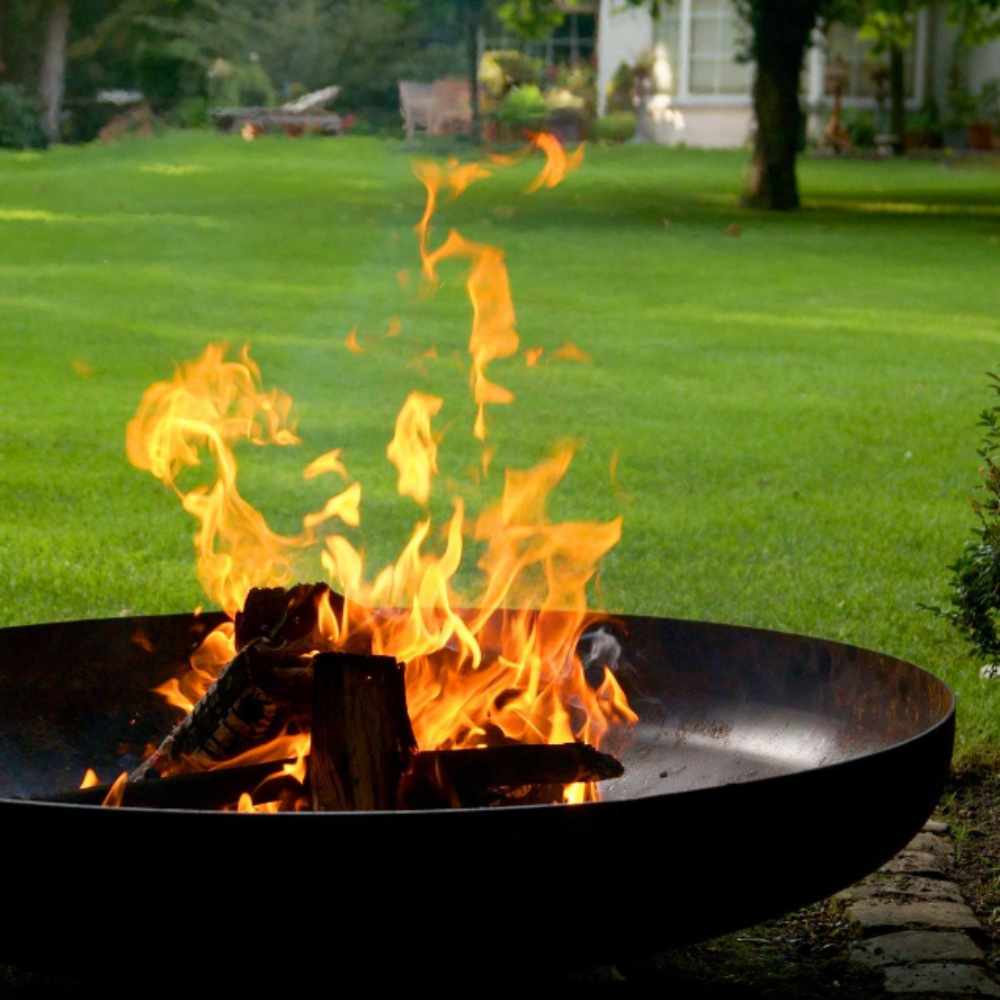 Fire pit with flames burning on a grassy lawn