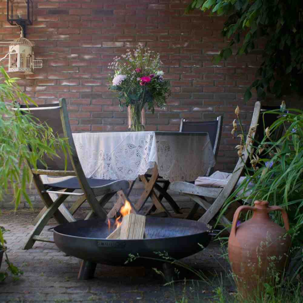 Outdoor setting with a fire pit, table, chairs, and decorative elements.