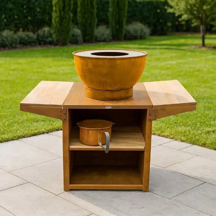 Wooden outdoor table with a large decorative fire pit on top, set against a garden background.