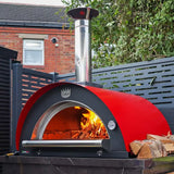Red outdoor pizza oven with fire inside, placed on a patio area.